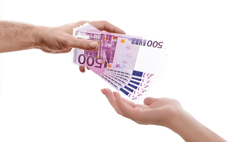 mano di uomo che porge diverse banconote da 500 euro alla mano di una donna