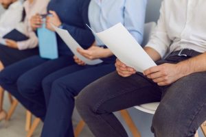 Candidati con curriculum in mano che aspettano di essere selezionati: candidato senior over 50 in primo piano