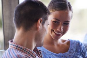Donna che guarda un uomo seduto accanto a lei con sguardo complice ed interessato