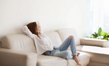 Ragazza seduta su divano chiaro guarda fuori dalla finestra