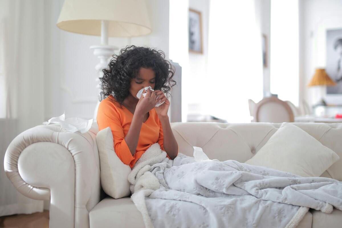 Ragazza sul divano che si soffia il naso