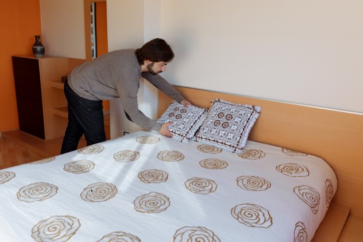 uomo che sistema cuscini sul letto