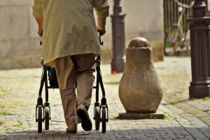 Anziano che cammina per strada con il deambulatore