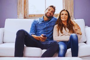 Coppia seduta sul divano che guarda la tv