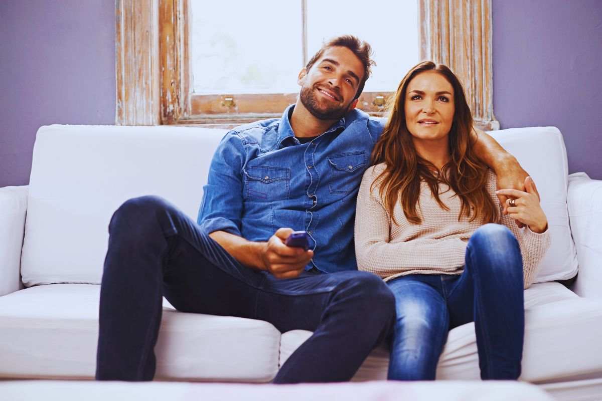 Coppia seduta sul divano che guarda la tv