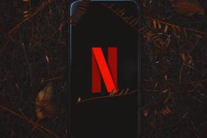 Telefono lasciato in mezzo al bosco con logo Netflix in evidenza sullo schermo