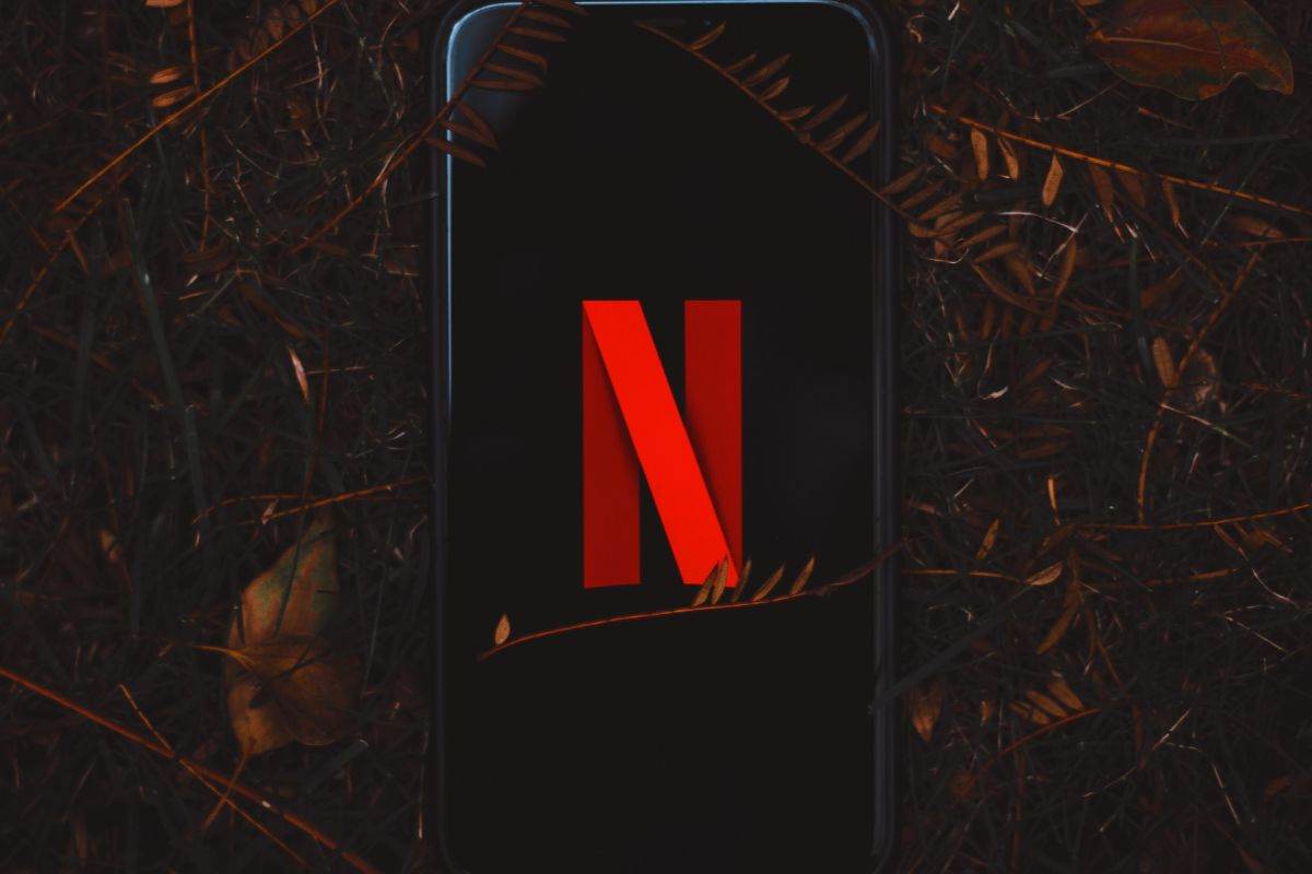 Telefono lasciato in mezzo al bosco con logo Netflix in evidenza sullo schermo