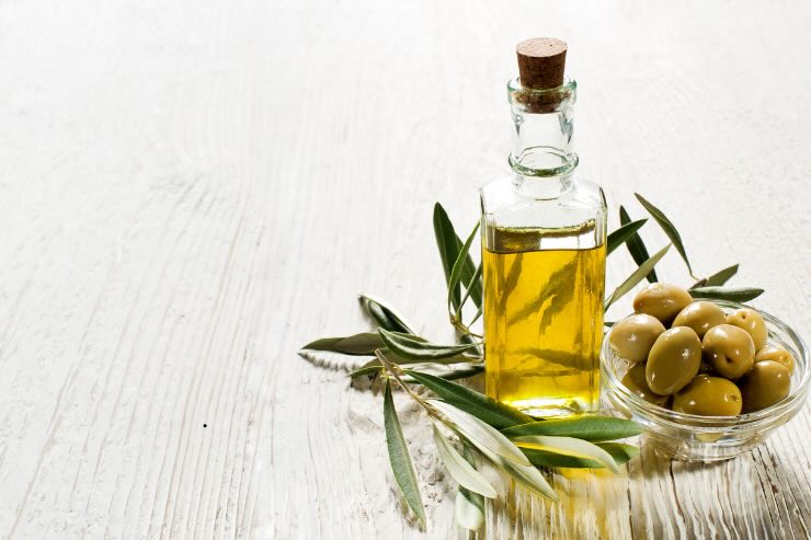 bottiglia olio d'oliva e olive in ciotola trasparente