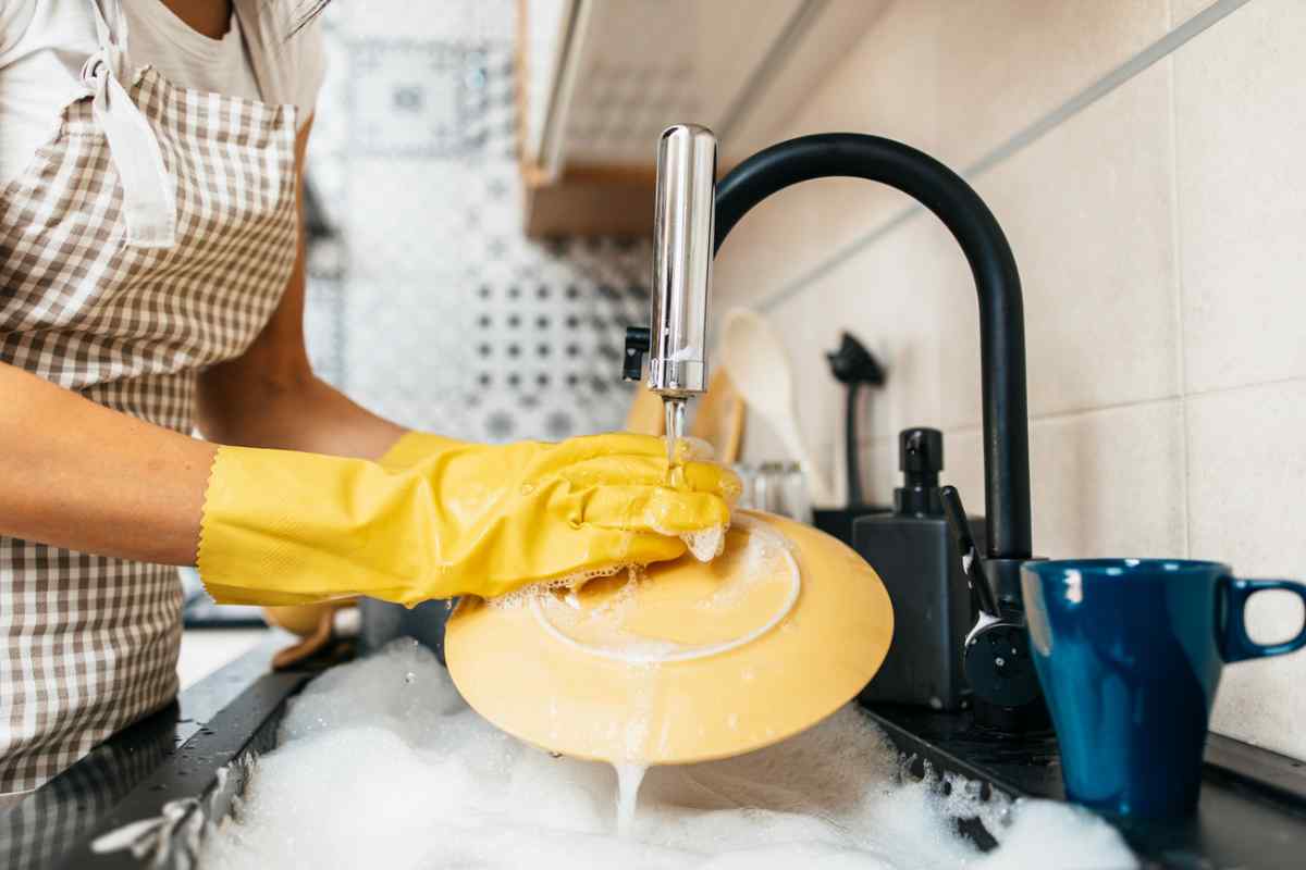 Persona che lava piatti con guanti
