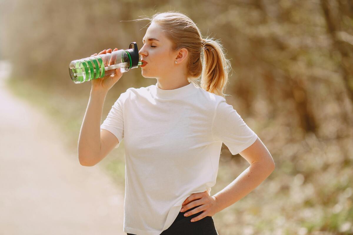 Ragazza che beve acqua da una borraccia