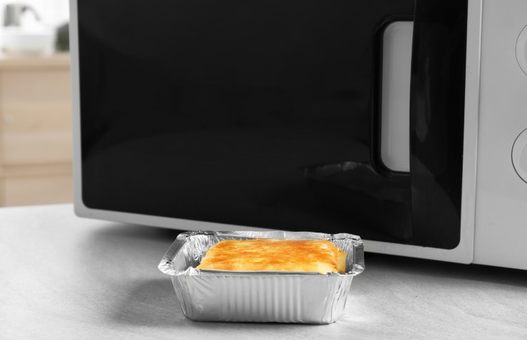 forno a microonde e vassoio di alluminio con cibo