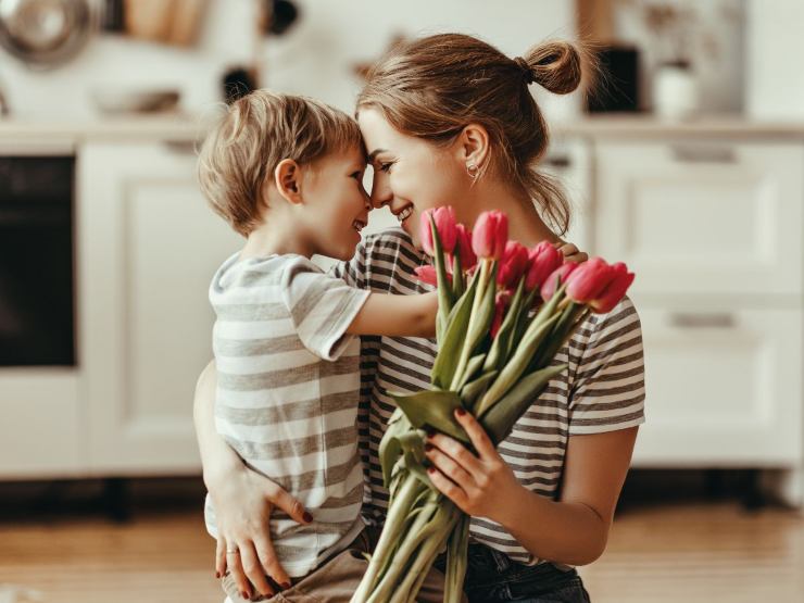 mamma e figlio abbracciati con fiori in mano