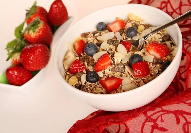 ciotola con cereali e frutta e accanto delle fragole