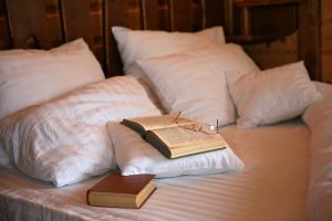 Letto con cuscini, due libri e occhiali da vista