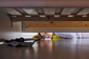 Donna che spazza sotto il letto