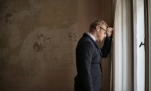 uomo disperato con la testa appoggiata contro il muro