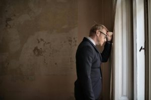 uomo disperato con la testa appoggiata contro il muro