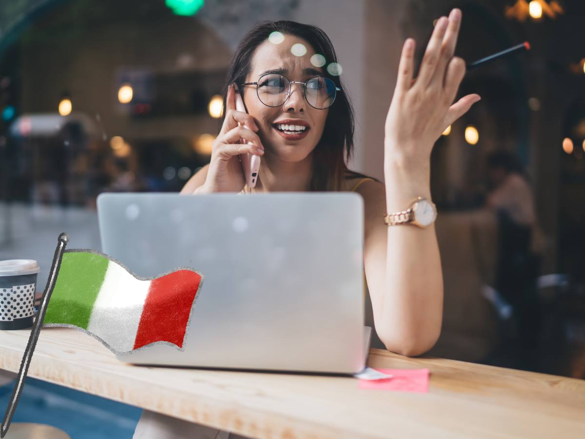 donna con pc davanti che parla a telefono e bandiera italiana