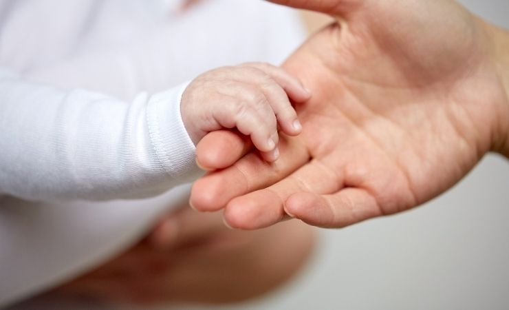 Neonato stringe mano genitore