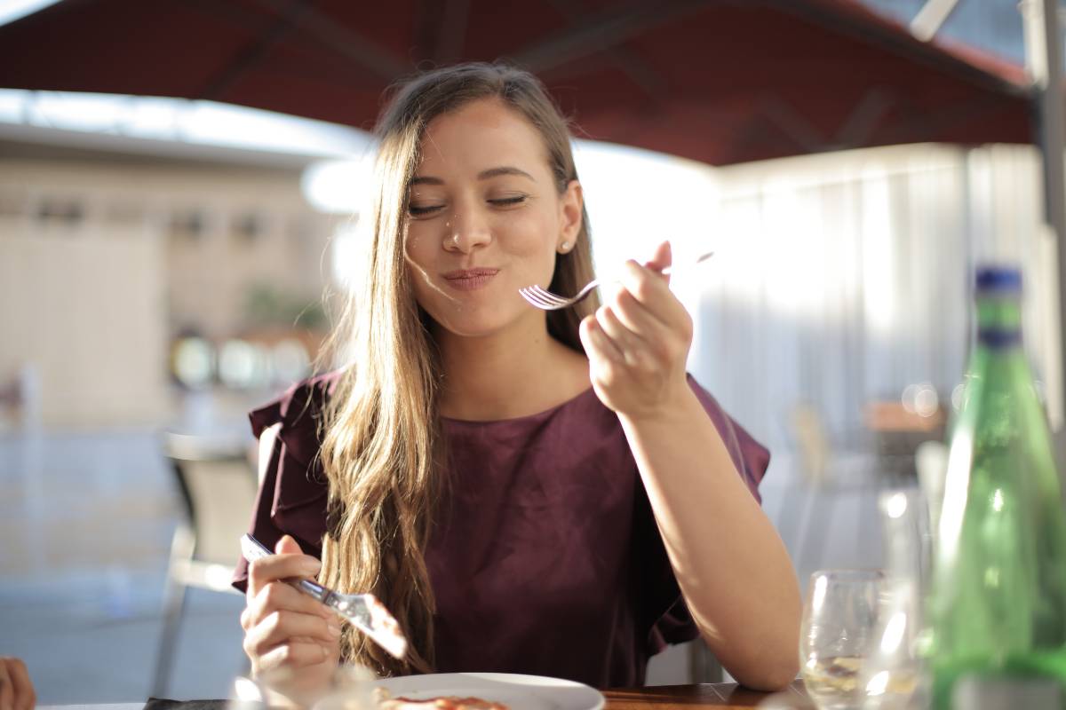 Ragazza con il metabolismo veloce che mangia soddisfatta