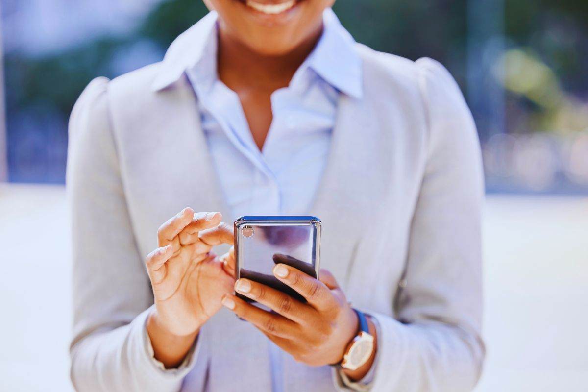 Donna sorridente mentre chatta con lo smartphone