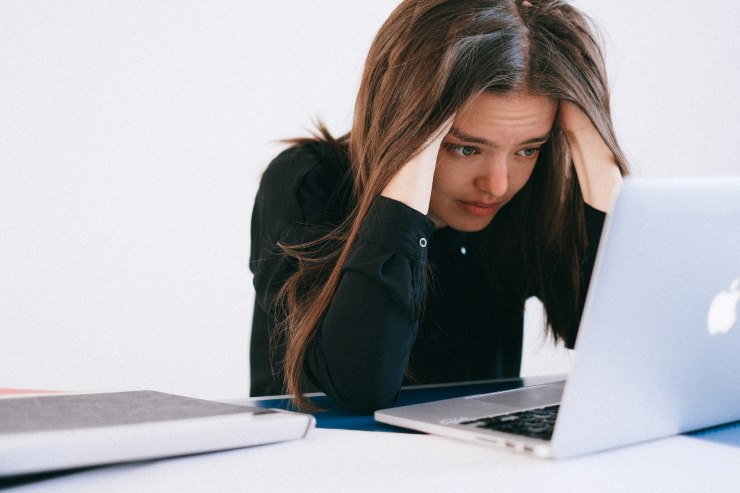donna disperata con mani tra i capelli di fronte a pc