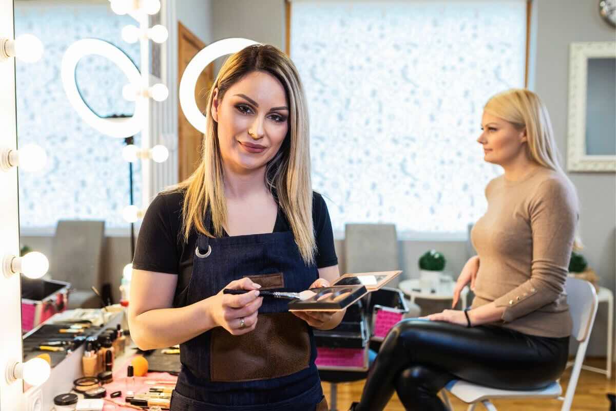 Make up artist con palette ombretti e sul fondo cliente