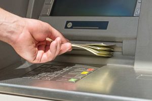 Mano che prende le banconote dal bancomat