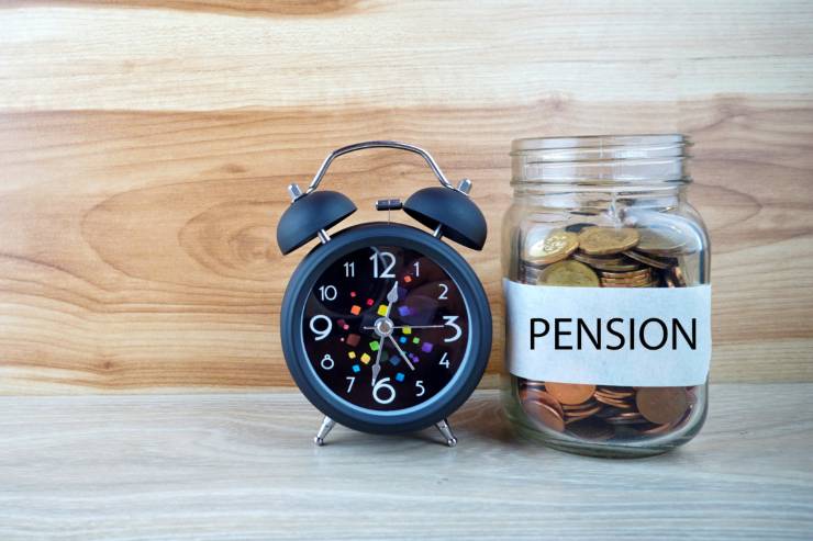 Sveglia e barattolo pieno di monete con scritto "pensione"
