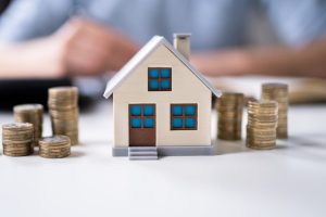 casa in miniatura e pile di monete