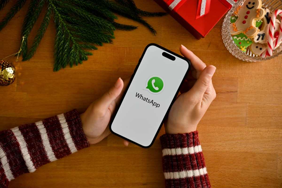 donna che tiene in mano smartphone con logo whatsapp