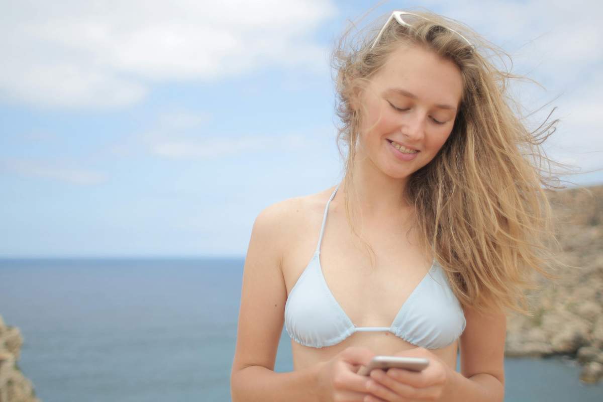 Ragazza in costume che guarda il telefono